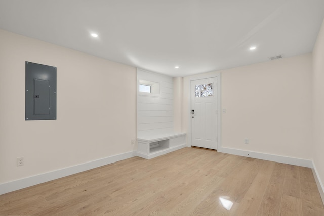 foyer entrance with visible vents, electric panel, light wood-style flooring, and baseboards