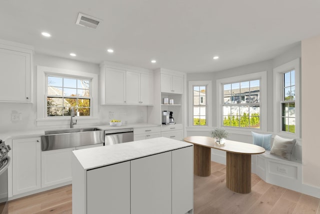 kitchen with breakfast area, visible vents, stainless steel dishwasher, a sink, and light wood-type flooring