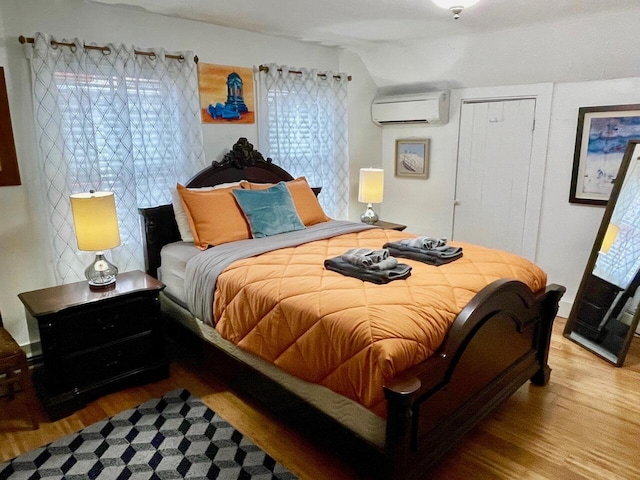 bedroom with wood-type flooring, lofted ceiling, and a wall mounted AC