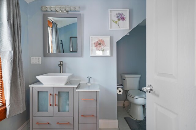 bathroom with toilet, vanity, and tile patterned flooring