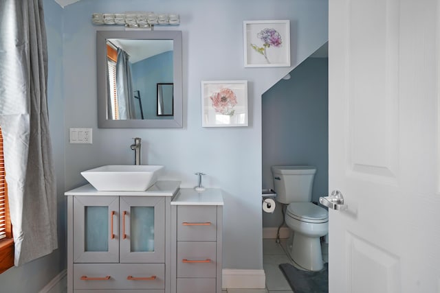 bathroom with toilet, vanity, and tile patterned flooring