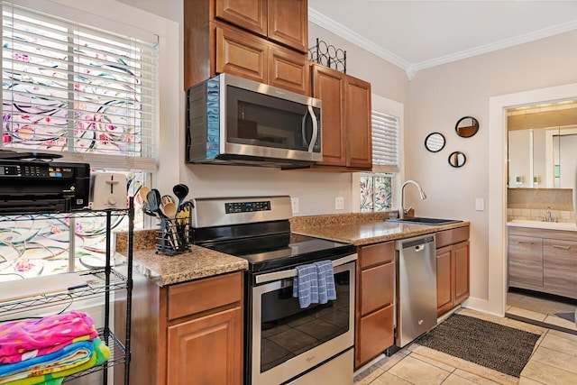 kitchen featuring light stone countertops, appliances with stainless steel finishes, sink, ornamental molding, and light tile patterned flooring