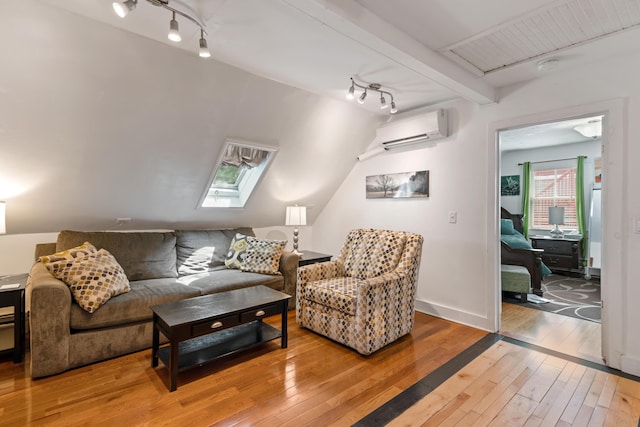 living room with wood-type flooring, vaulted ceiling with skylight, and an AC wall unit