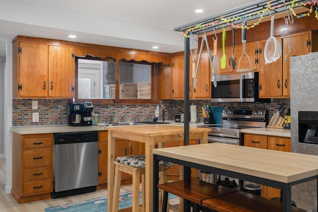 kitchen with decorative backsplash, sink, appliances with stainless steel finishes, and light hardwood / wood-style flooring