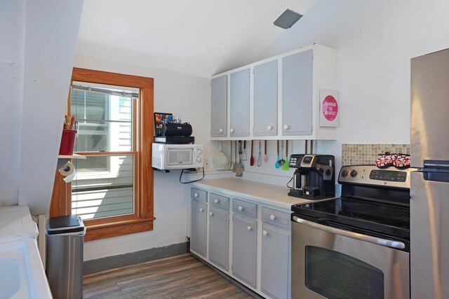 kitchen featuring vaulted ceiling, dark wood-type flooring, and stainless steel range with electric cooktop