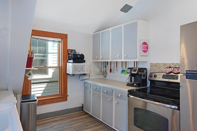 kitchen featuring vaulted ceiling, dark wood-type flooring, and stainless steel range with electric cooktop
