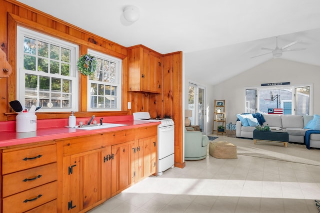 kitchen featuring wooden walls, sink, white range oven, vaulted ceiling, and ceiling fan