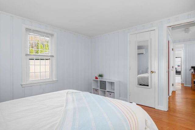 bedroom with light hardwood / wood-style floors and a wall unit AC