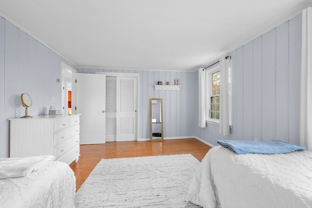 bedroom featuring light hardwood / wood-style flooring, ornamental molding, and wooden walls