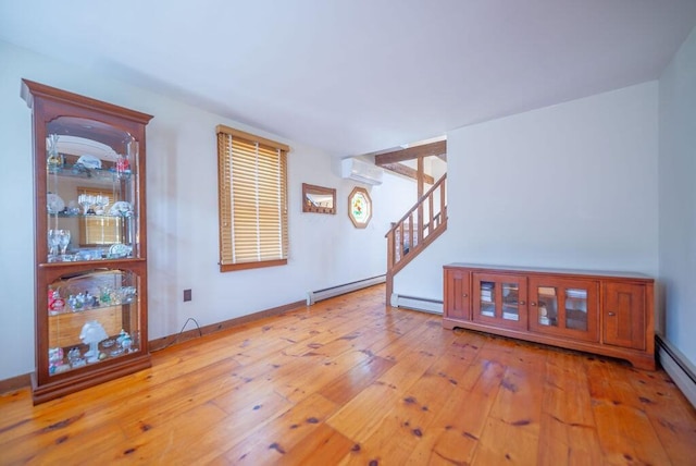 12 Tree Top Ln, East Falmouth, MA 02536 - living room featuring an AC wall unit, a baseboard radiator, a baseboard heating unit, stairs, and wood-type flooring