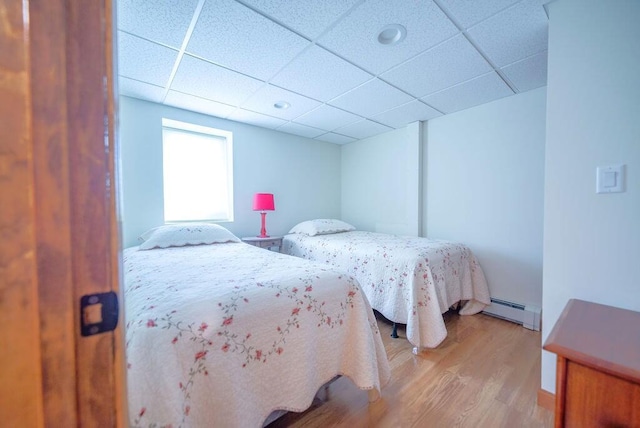 12 Tree Top Ln, East Falmouth, MA 02536 - bedroom with a baseboard heating unit, light wood-type flooring, and a paneled ceiling
