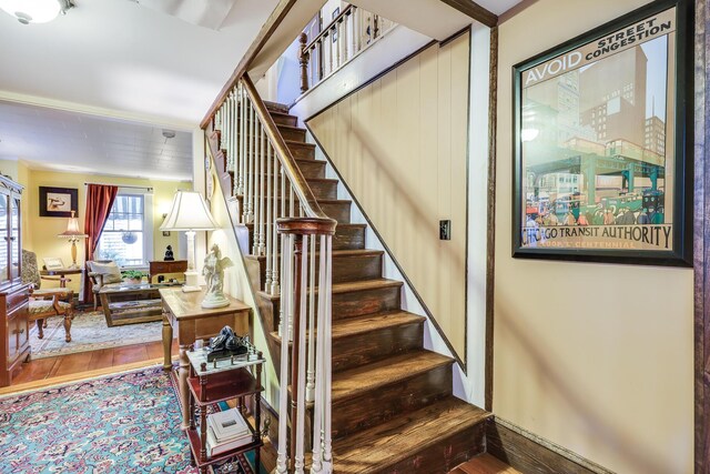 stairs with hardwood / wood-style flooring and crown molding