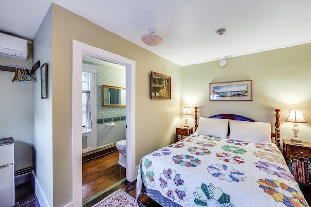 bedroom featuring a wall mounted AC, dark wood-type flooring, and ensuite bath