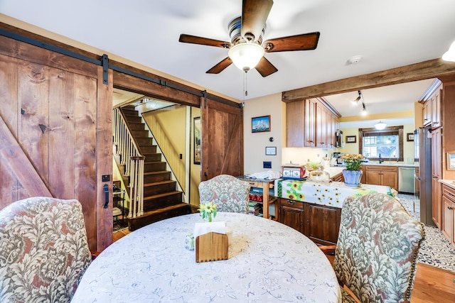 dining room featuring ceiling fan, a barn door, and light hardwood / wood-style floors