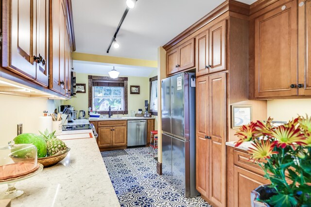 kitchen with light stone counters, sink, stainless steel appliances, and rail lighting