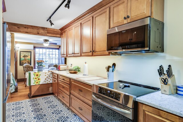 kitchen with an AC wall unit, stainless steel appliances, ceiling fan, light stone counters, and beam ceiling