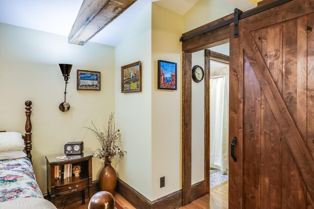 bedroom with hardwood / wood-style flooring and a barn door