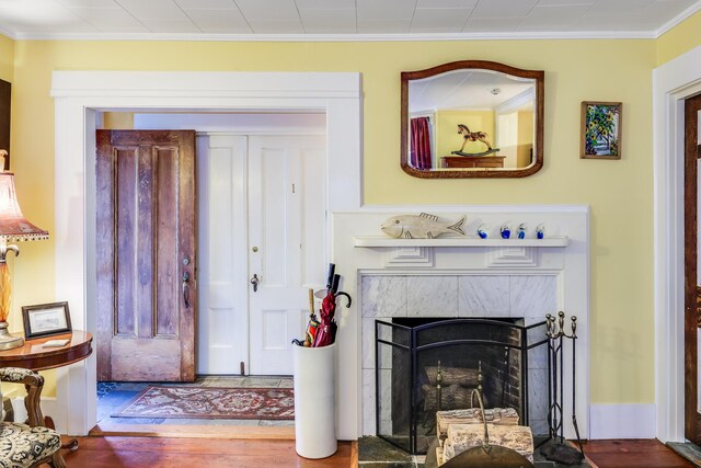 interior space with wood-type flooring, ornamental molding, and a fireplace