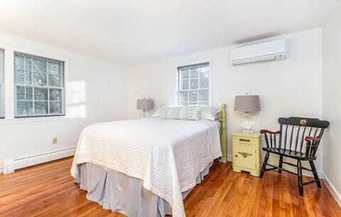 bedroom featuring hardwood / wood-style floors, a baseboard radiator, and an AC wall unit