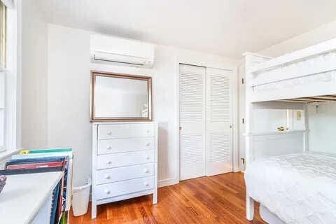 bedroom featuring a wall mounted air conditioner, a closet, and light wood-type flooring