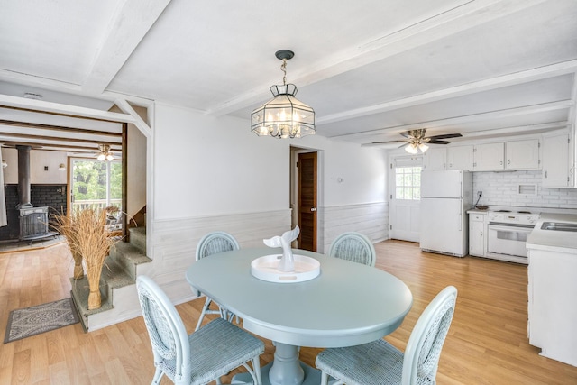 190 Meadow Ave W, Wellfleet, MA 02667 - dining area with a wood stove, beamed ceiling, wainscoting, light wood-style floors, and ceiling fan