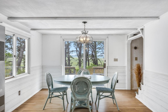 190 Meadow Ave W, Wellfleet, MA 02667 - dining area featuring a chandelier, beamed ceiling, plenty of natural light, light wood-style flooring, and wainscoting