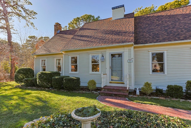 view of front of property with a shingled roof, a chimney, and a front yard