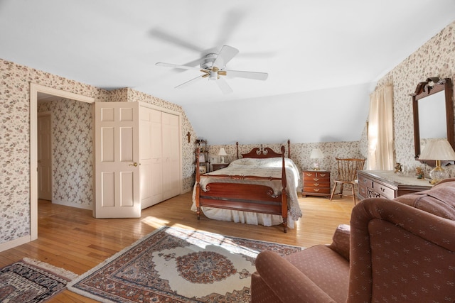 bedroom featuring lofted ceiling, light hardwood / wood-style floors, a closet, and ceiling fan