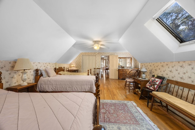 bedroom featuring ceiling fan, vaulted ceiling with skylight, and hardwood / wood-style flooring