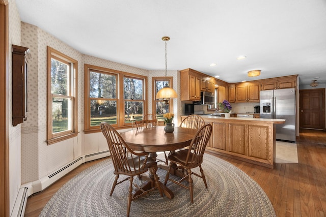 dining space with hardwood / wood-style floors and a baseboard heating unit