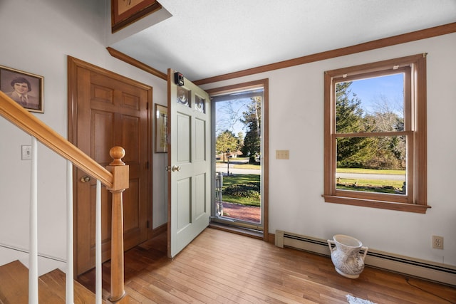 foyer with light wood-type flooring, crown molding, and a baseboard radiator