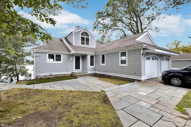 view of front of house with an attached garage, a chimney, concrete driveway, and roof with shingles