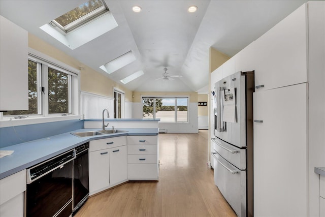 kitchen with vaulted ceiling with skylight, white cabinets, dishwasher, stainless steel refrigerator with ice dispenser, and a sink