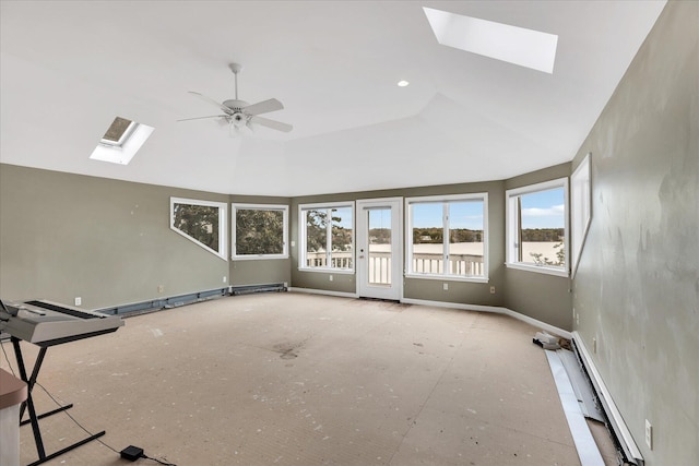 unfurnished room with a baseboard heating unit, ceiling fan, a tray ceiling, and a skylight