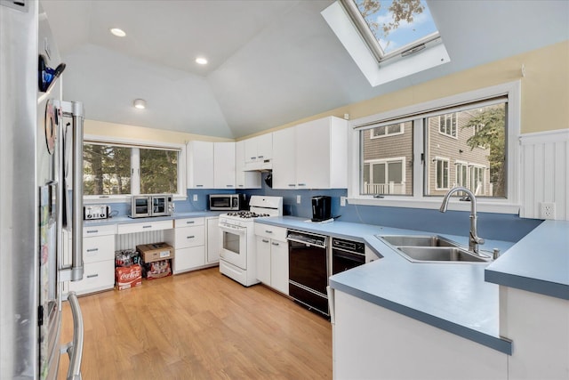 kitchen with stainless steel appliances, a sink, under cabinet range hood, and lofted ceiling with skylight