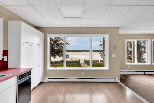 kitchen featuring a healthy amount of sunlight, a baseboard radiator, and white cabinetry