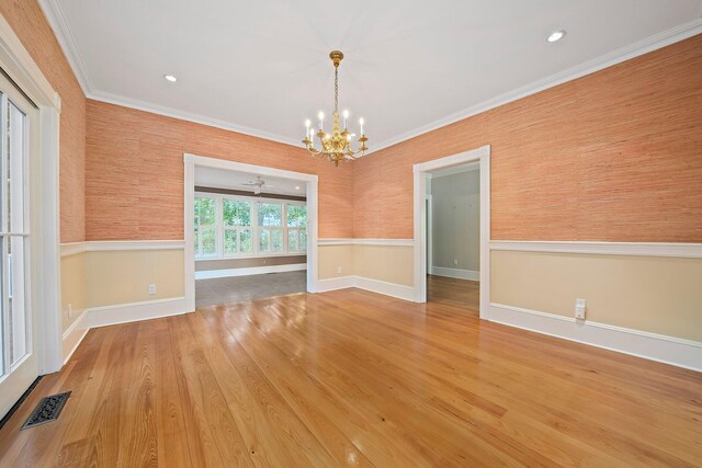 empty room featuring wood-type flooring, ceiling fan with notable chandelier, and ornamental molding