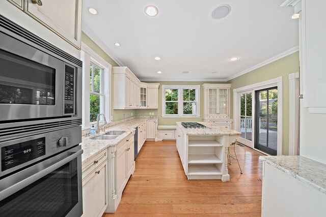 kitchen featuring a center island, a kitchen bar, light stone countertops, appliances with stainless steel finishes, and sink