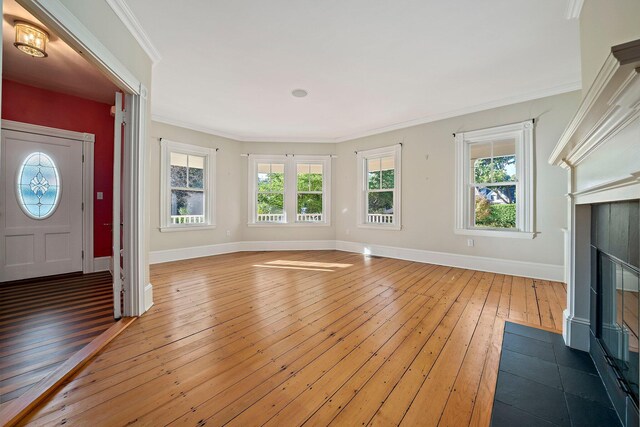 unfurnished living room with crown molding, a wealth of natural light, and dark hardwood / wood-style flooring