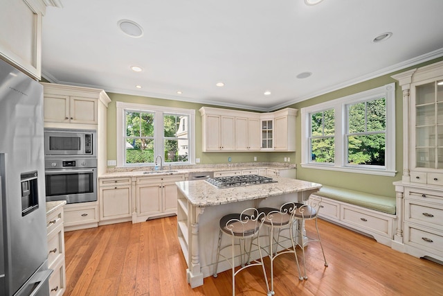 kitchen with a kitchen bar, appliances with stainless steel finishes, a center island, and cream cabinetry