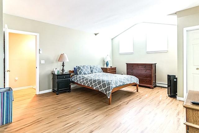 bedroom with a baseboard heating unit, baseboards, and wood finished floors