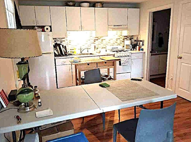 kitchen featuring white gas stove, backsplash, white cabinets, a sink, and ventilation hood