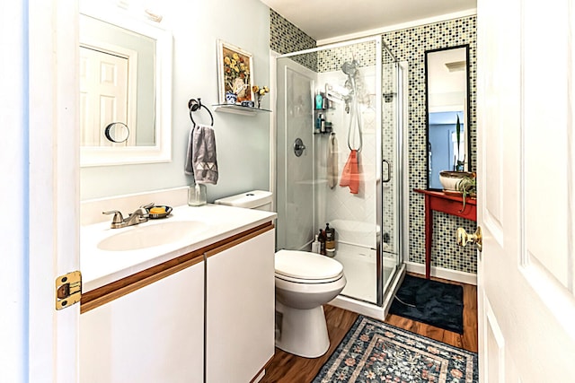 bathroom featuring a stall shower, vanity, toilet, and wood finished floors