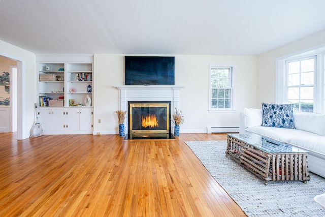 living area featuring light wood finished floors, baseboard heating, a fireplace with flush hearth, and baseboards