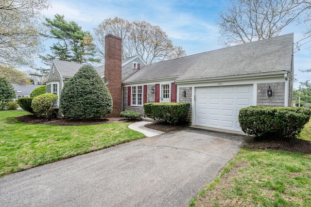 view of front facade with a garage, driveway, a chimney, a front lawn, and roof with shingles
