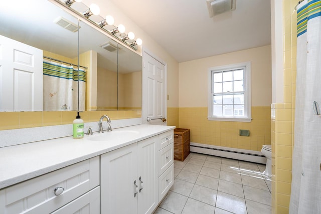 bathroom with a baseboard radiator, tile walls, tile patterned flooring, a wainscoted wall, and vanity