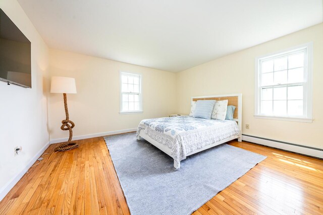 bedroom featuring baseboard heating, wood-type flooring, and baseboards