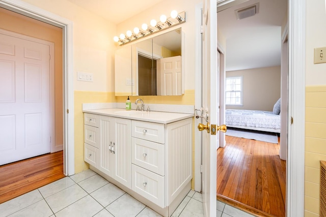 bathroom with tile patterned floors, vanity, wainscoting, and ensuite bathroom
