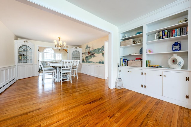 dining area featuring a wainscoted wall, a chandelier, light wood-style floors, a decorative wall, and built in features