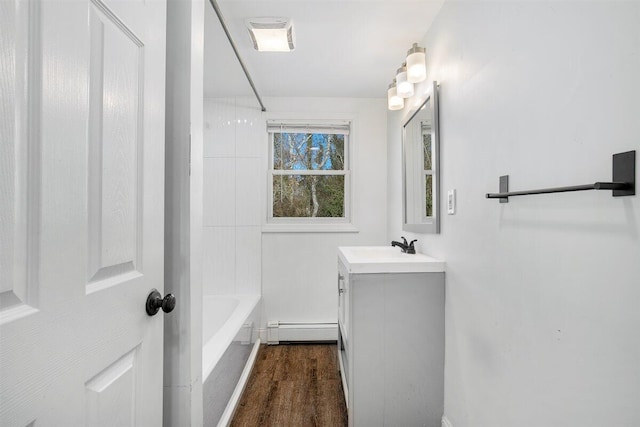 bathroom with vanity, a baseboard heating unit, hardwood / wood-style floors, and bathing tub / shower combination